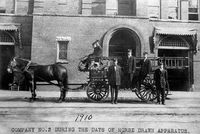 Firemen, Company 2 (1910): Six firemen in full uniform pose by their horse-drawn hose and ladder wagon in front of Fire Station #2, located on West Main Street, between two Liggett & Myers warehouses. To provide better protection for Erwin Mills, Trinity College and Watts Hospital, Company 2 was eventually moved to its present location at Ninth and Knox.