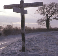 Signpost at junction of Long Lane and The Rosery - now the post has gone, the road here 'improved' and the field behind the hedge is full of houses.