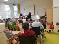 uživatelé sledující vystoupení ve společenském sále domova