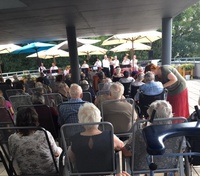 uživatelé sledující vystoupení MUZIKANTŮ z jižních Čech na terase domova