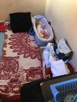 Hemma hos en ensamstående mamma och hennes bebis. Hon sover på den röd-vita filten på golvet, och bebisen i sin lilla bebiskorg (eller vad det kallas?)