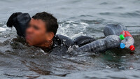 Un niño marroquí nada usando botellas como flotador mientras cruza la frontera entre Marruecos y España. Ceuta, 19 de mayo de 2021. Jon Nazca / Reuters