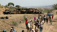 Personas pasan entre vehículos quemados en su camino de regreso de un mercado, en Tigray, Etiopía, el 10 de julio de 2021. Giulia Paravicini / Reuters